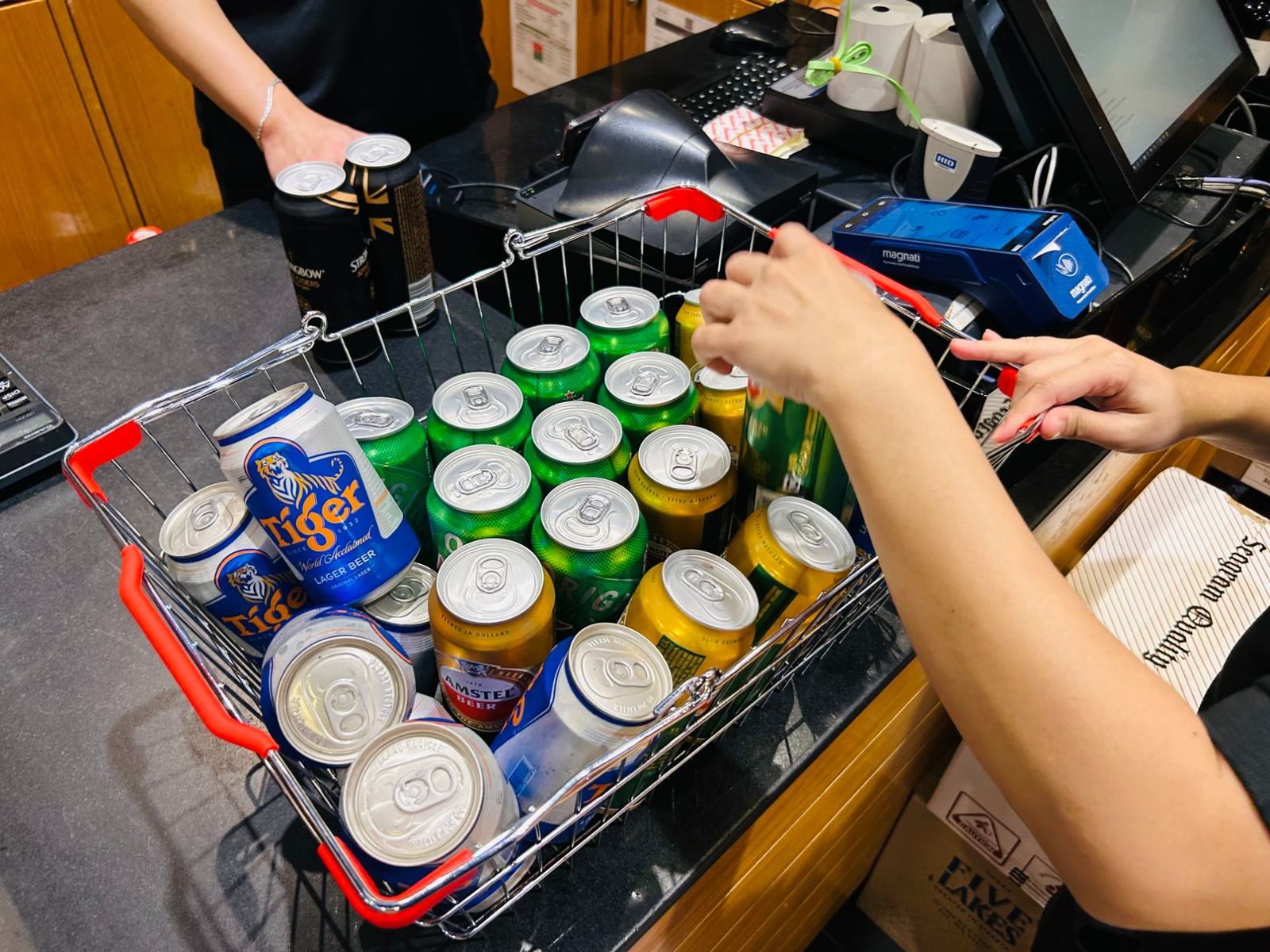 酒類専門店のレジ。ビールの缶を詰めた買い物かごを会計している